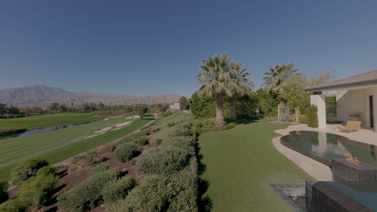 Low aerial crossing the golf course toward the house
