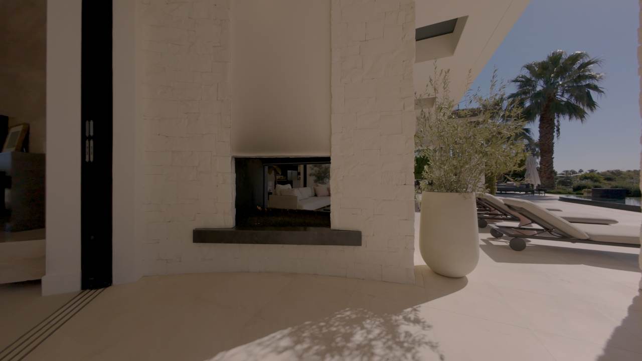 Covered loggia with an outdoor fireplace beside the pool